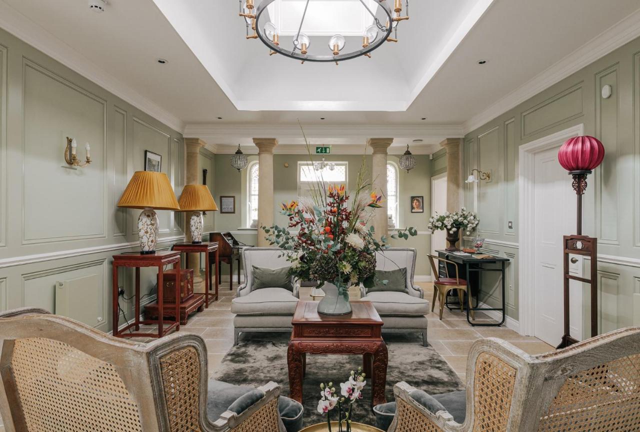 a living room with chairs and a table with a vase of flowers at Tyndall Villa Boutique B&B in Bath
