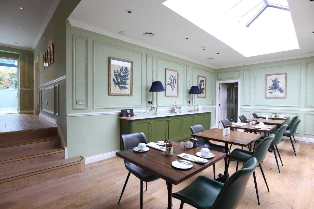 a dining room with wooden tables and green walls at Tyndall Villa Boutique B&B in Bath